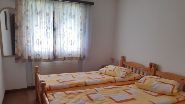 Ein Zimmer mit zwei Holzbett, einer Heizung und einem Fenster mit gemusterten Vorhängen.