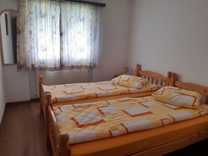 A room with two wooden beds, a radiator, and a window with patterned curtains. - Wohnung Bergruh Appartement/Fewo, Dusche, WC 2-Bettwohnung by Interhome (Rosswald)