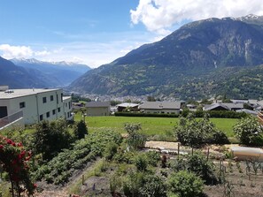 Un quartier résidentiel avec des maisons, un jardin et des montagnes en arrière-plan.
