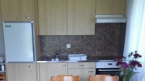 Eine Küche mit Holzausstattung, einem Einbauofen, einem Spülbecken und einem Esstisch mit Stühlen.