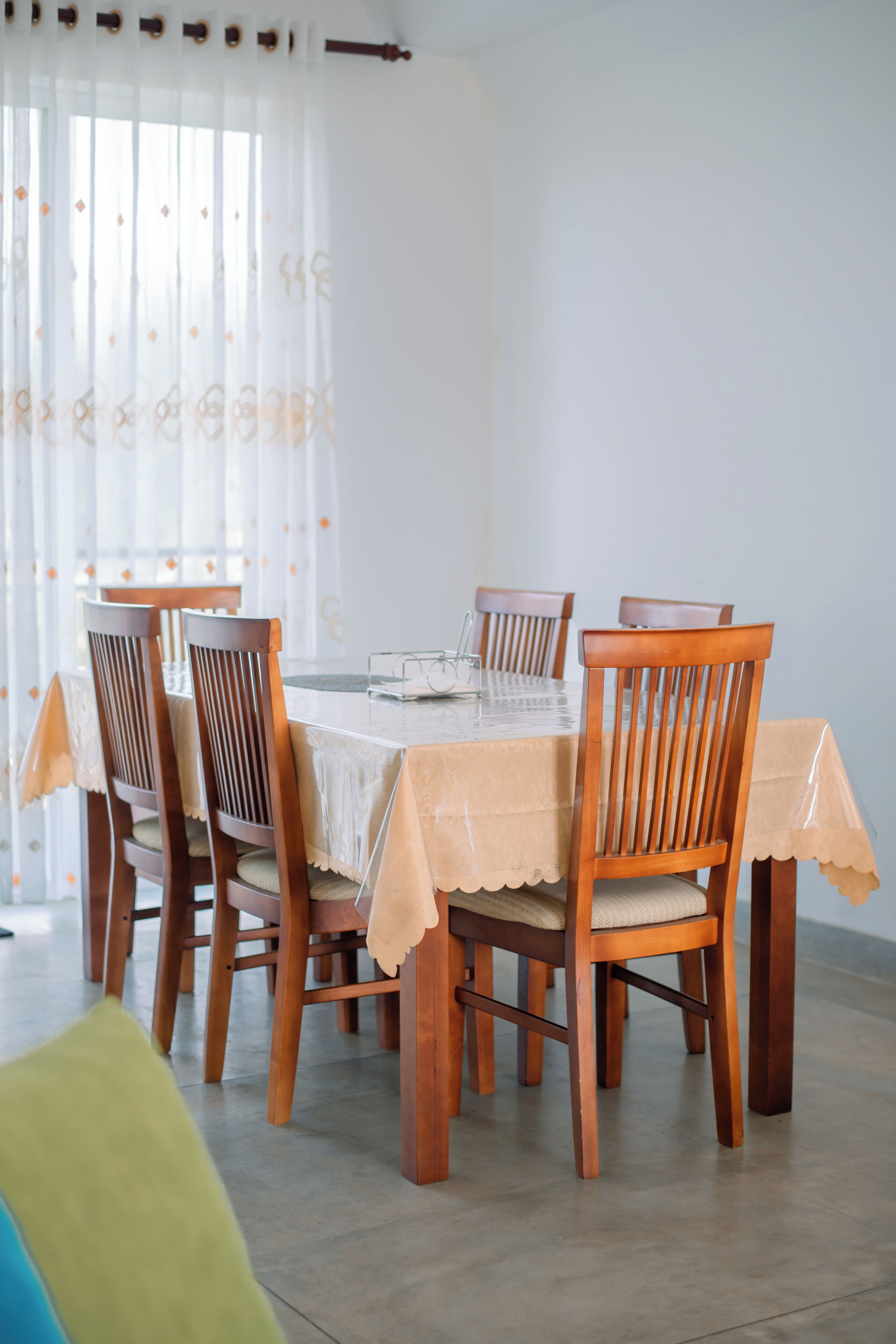 A dining area with a round table and six wooden chairs, each with a cushion.