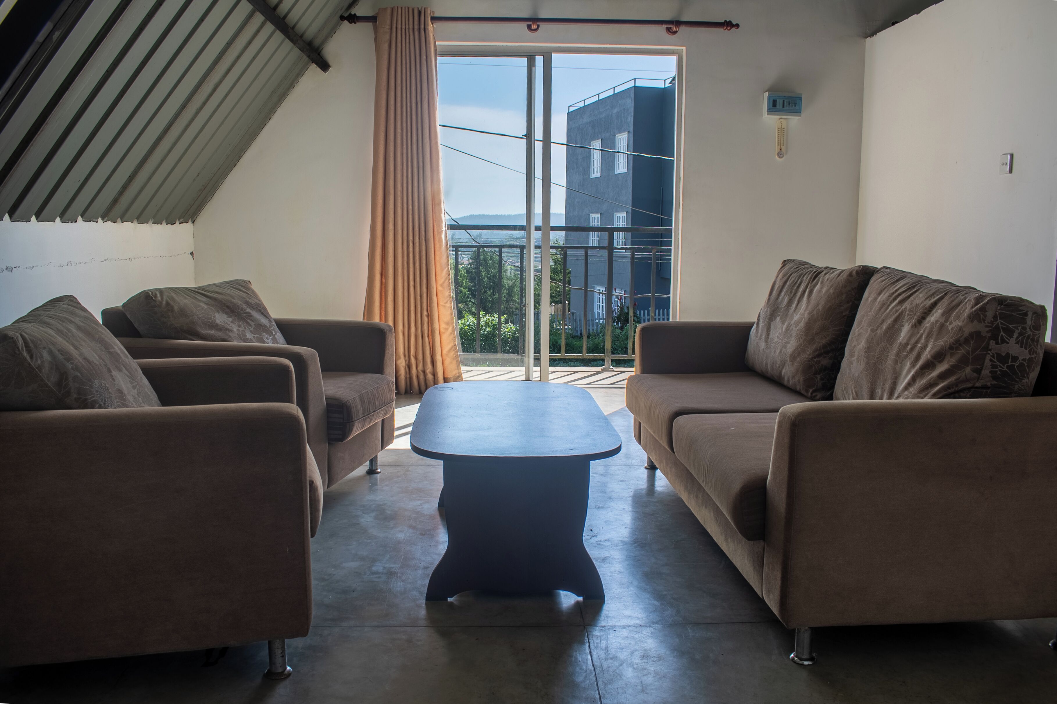 A living room with two sofas, a coffee table, and a view of a building through a glass door.