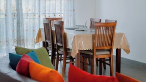 En spiseplads med et bord, stole og en sofa med farverige puder.