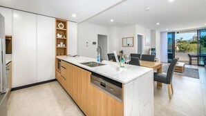 Et moderne køkken med en central ø, integrerede hårde hvidevarer og et spiseområde med udsigt.