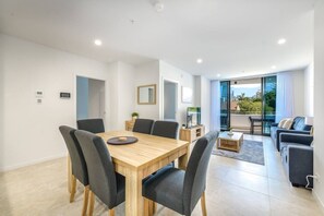 Ein zeitgemäßer Wohnbereich mit Essbereich, Sitzgelegenheiten und einem Balkon mit Blick auf die Stadt.