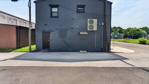 A small, single-story building with a dark gray exterior, a door, and a window. - Iconic urban Bourbon Trail suite with EV charger! (Louisville)