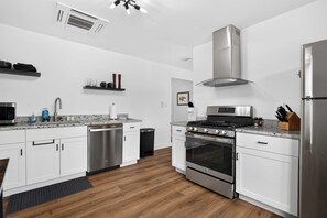 Een moderne keuken met witte kasten, roestvrijstalen apparatuur en een houten vloer.