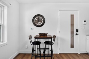 Ein Essbereich mit einem Holztisch, zwei Stühlen und einer an der Wand befestigten Uhr.