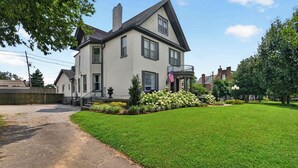 Une maison à deux étages avec une pelouse bien entretenue, un porche à l’avant et un drapeau.