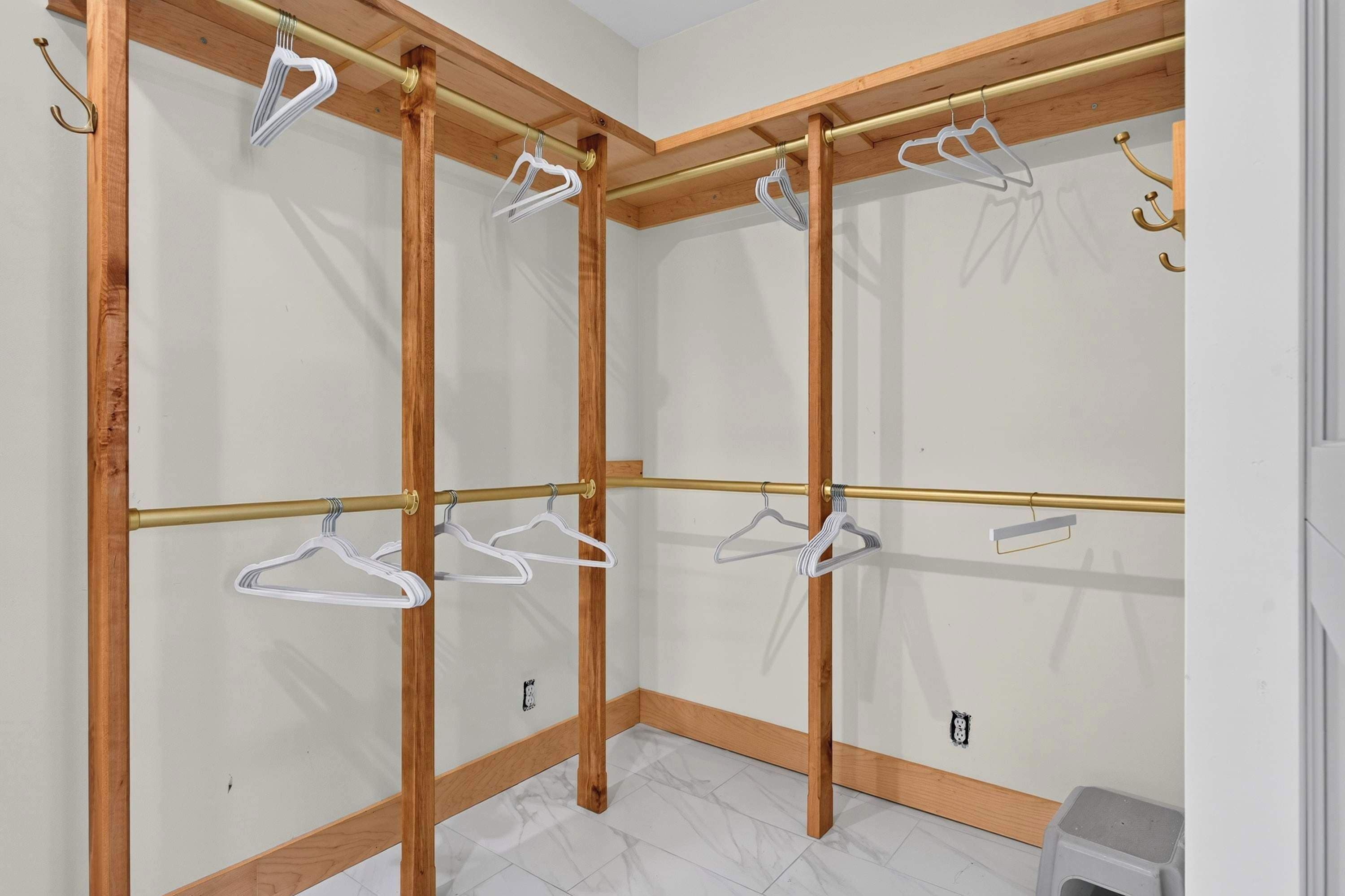 Un dressing avec des étagères en bois et de nombreux espaces pour suspendre les vêtements.