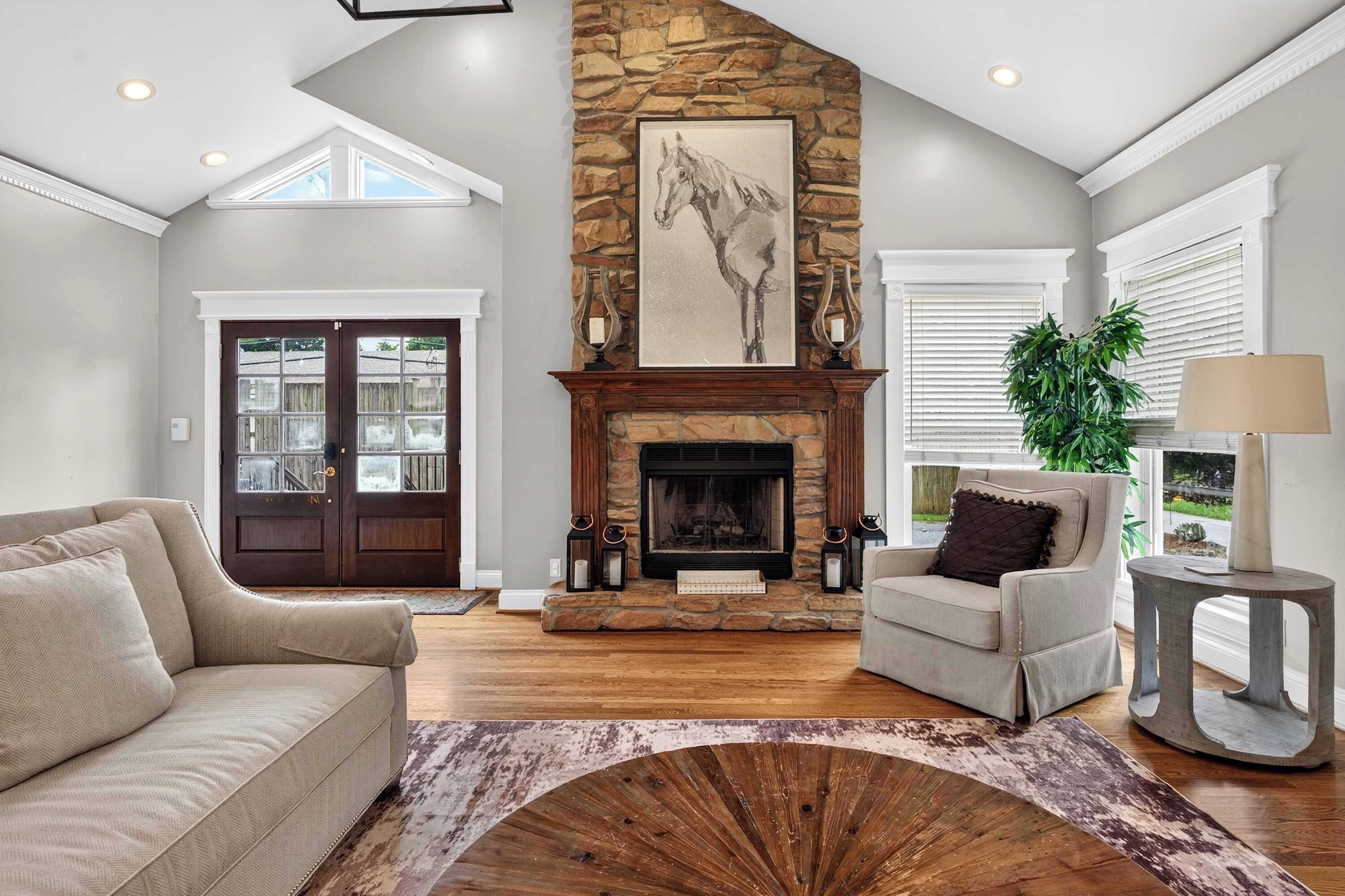 A spacious living room with a stone fireplace, a large window, and a cozy seating area.