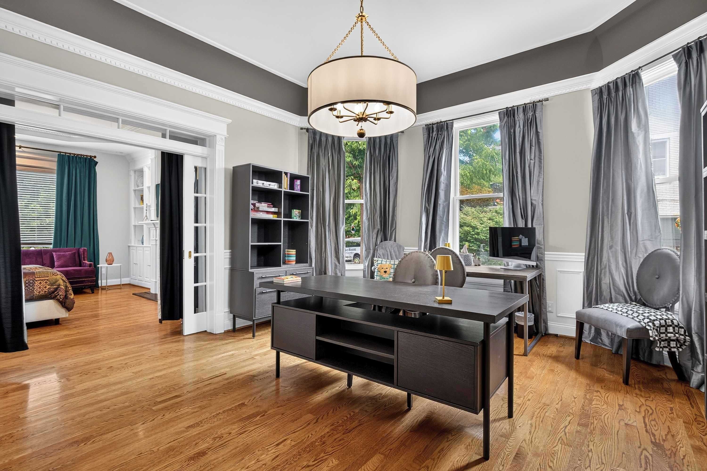 A modern living room with a dining area, a bookshelf, and a television.
