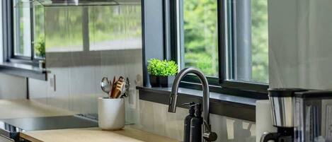 Uma cozinha moderna com uma ilha grande, eletrodomésticos de aço inoxidável e uma janela com vista para o verde.
