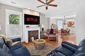 Ein modernes Wohnzimmer mit Kamin, Fernseher und Essbereich.