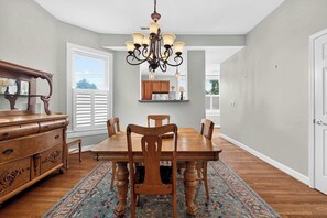A dining area with a wooden table, chairs, a chandelier, and a patterned rug. - Stylish 2-Bed Louisville Apt | Walkable & Bright (Louisville)