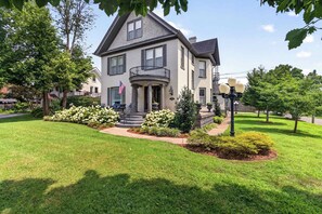 A two-story house with a balcony, a well-maintained lawn, and a flag. - Stylish 2-Bed Louisville Apt | Walkable & Bright (Louisville)