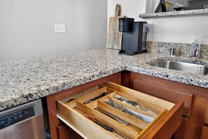 Eine Küche mit Granit-Arbeitsplatten, einer Kaffeemaschine, einem Spülbecken und einem Schubladeneinsatz für Besteck.