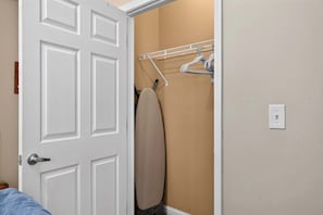 Ein Zimmer mit weißer Tür, einer beige farbenen Wand und einem Kleiderständer mit Kleiderbügeln.