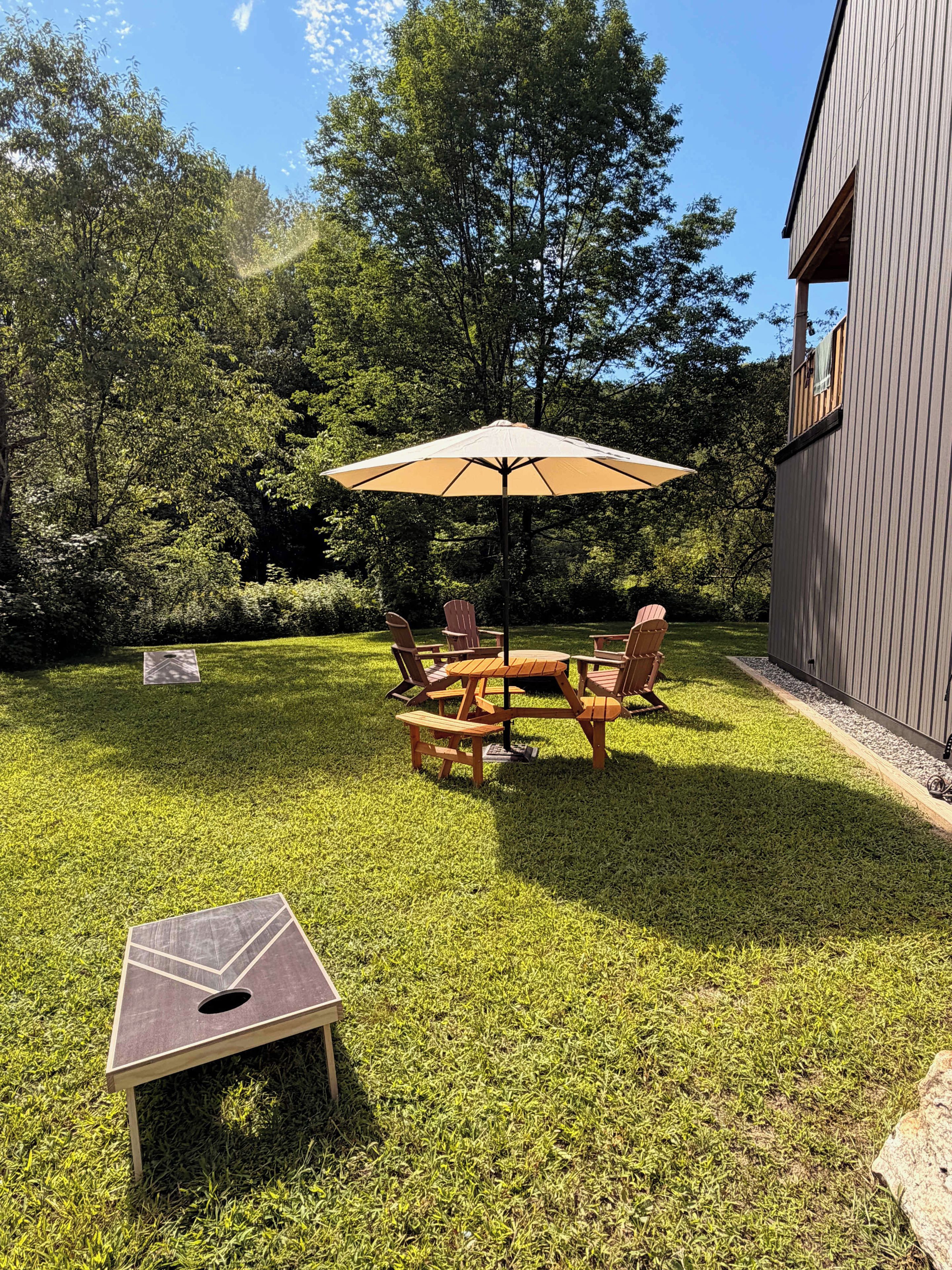 A patio area with a table and chairs, a wooden deck, and a building in the background.