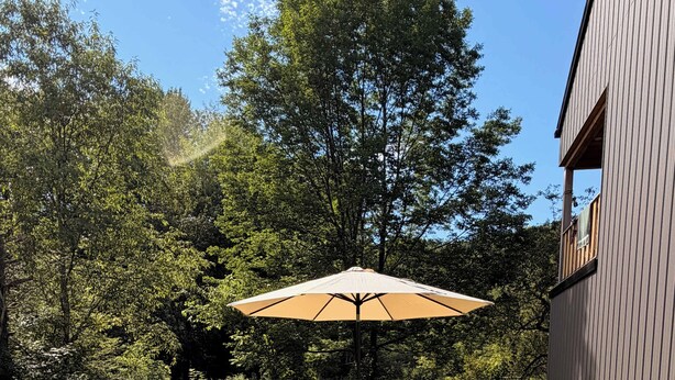 Un espace patio avec une table et des chaises, une terrasse en bois et un bâtiment en arrière-plan.