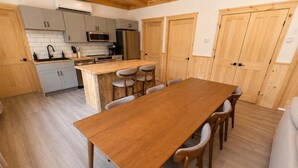 Une cuisine moderne avec des meubles de couleur grise, une table à manger en bois et un four encastré.