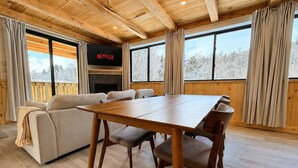 Une pièce chaleureuse avec un plafond en bois, un canapé, une table à manger et une cheminée.