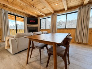 Una stanza accogliente con soffitto in legno, un divano, un tavolo da pranzo e un camino.