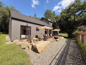 Une maison moderne dotée d’un patio aménagé avec des meubles d’extérieur et des parasols.