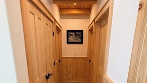 Un pasillo estrecho con paneles de madera y puertas, que conduce a una habitación con un cuadro enmarcado en la pared.
