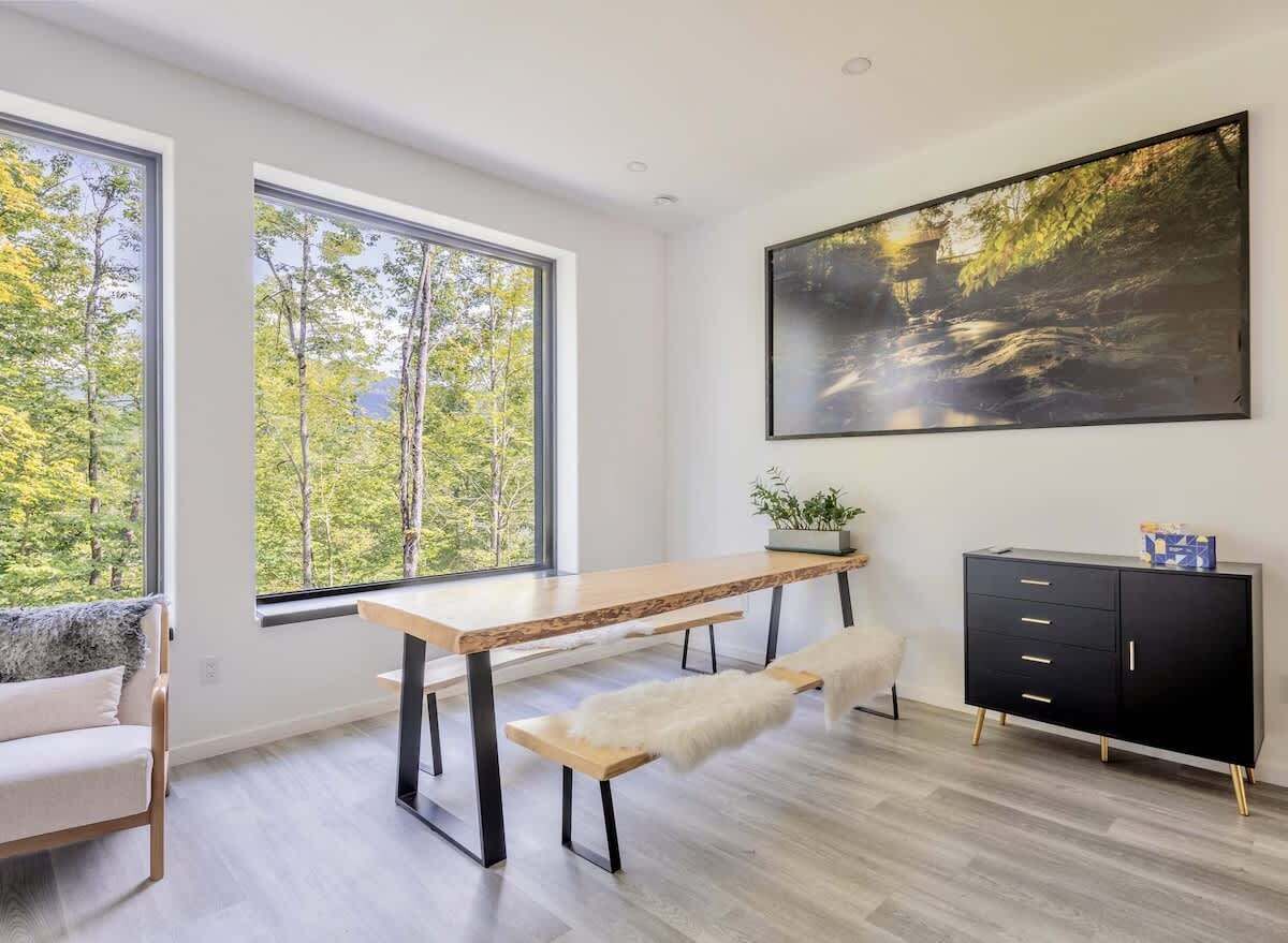 A modern room with a wooden desk, bench, and black cabinet with gold legs.