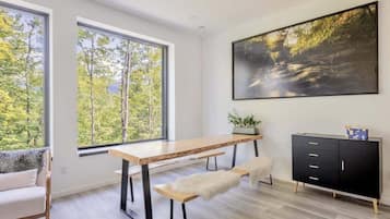 A modern room with a wooden desk, bench, and black cabinet with gold legs.