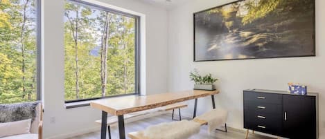 A modern room with a wooden desk, bench, and black cabinet with gold legs.