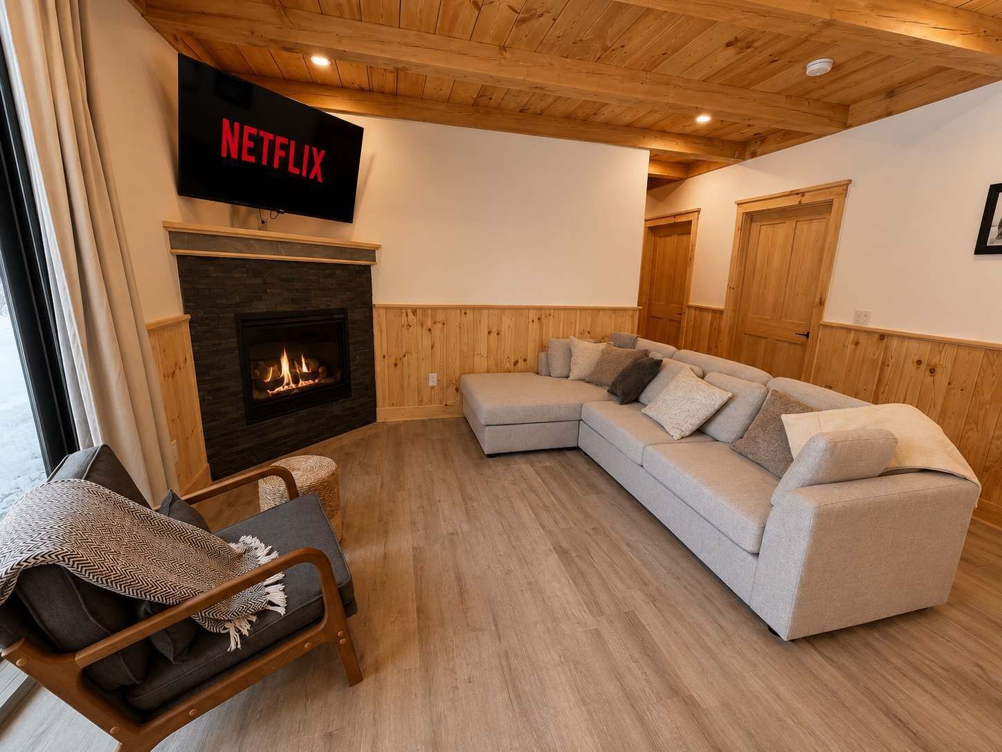 A living room with a fireplace, a sectional sofa, and a Netflix sign on the wall.