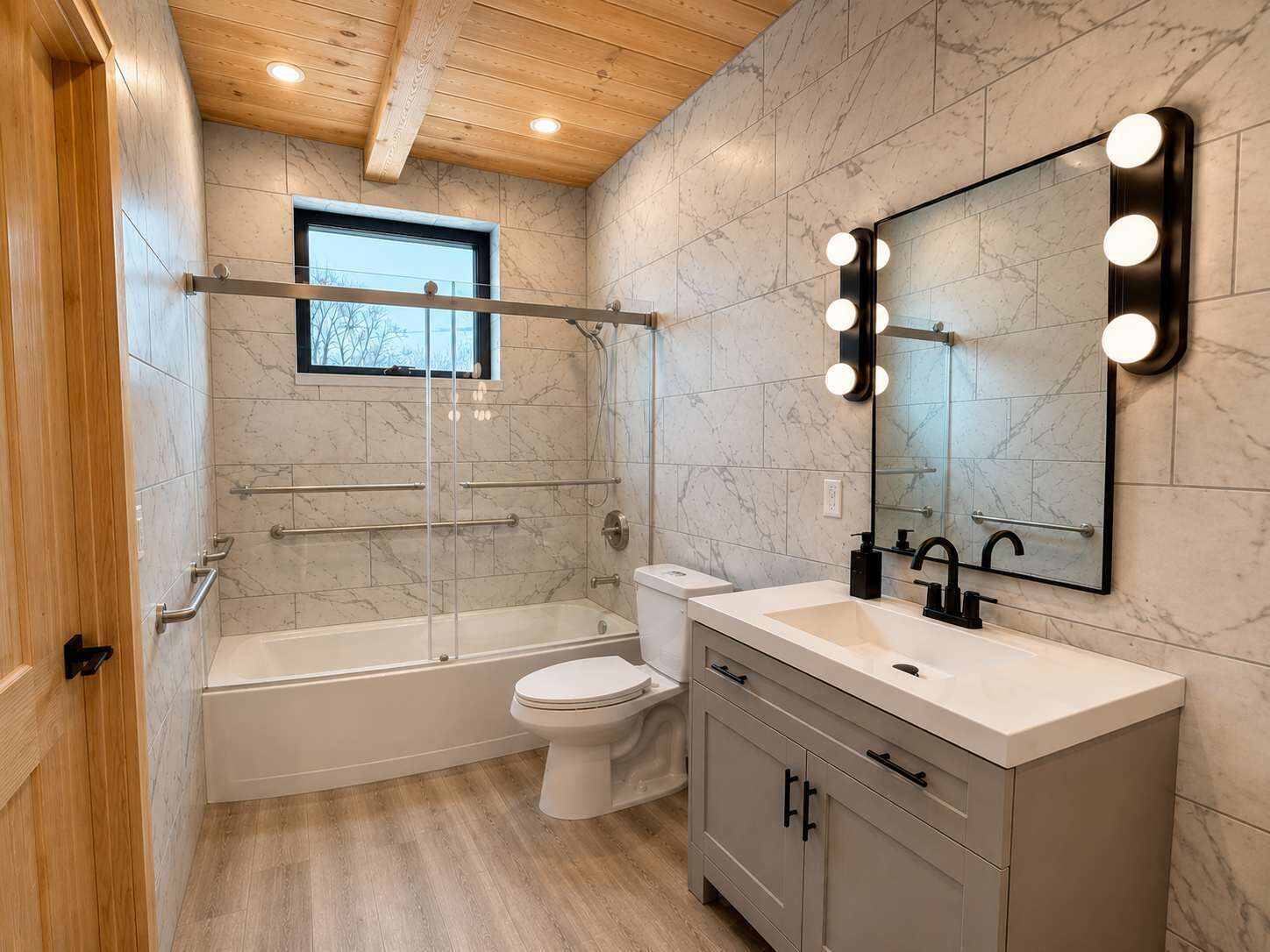 Ein modernes Badezimmer mit Badewanne, Toilette, Waschtisch und einem großen, beleuchteten Spiegel.