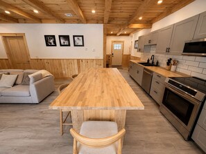 A modern kitchen with wooden flooring, a central island, and built-in appliances. - Bear Hearth | Nordic Barn, Stowe Nature Escape (Stowe)