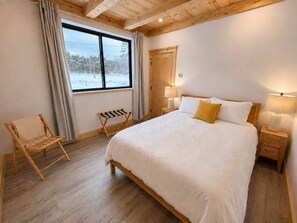 A bedroom with a large bed, wooden headboard, two bedside tables with lamps, a bench, and a window with curtains. - Bear Hearth | Nordic Barn, Stowe Nature Escape (Stowe)