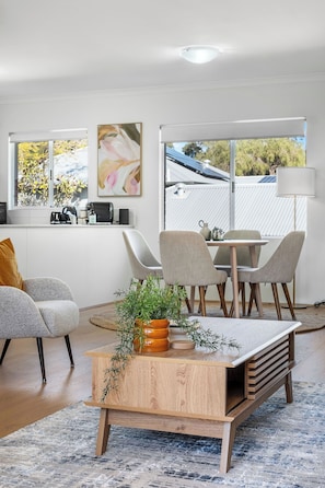 Un salon moderne avec une table basse en bois, un canapé et un coin repas comprenant des chaises et une table.