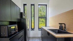 Eine moderne Küche mit eingebauten Geräten, einer Holz Arbeitsplatte und Blick durch drei Fenster.
