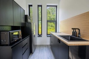 Uma cozinha moderna com eletrodomésticos embutidos, bancada de madeira e vista através de três janelas.