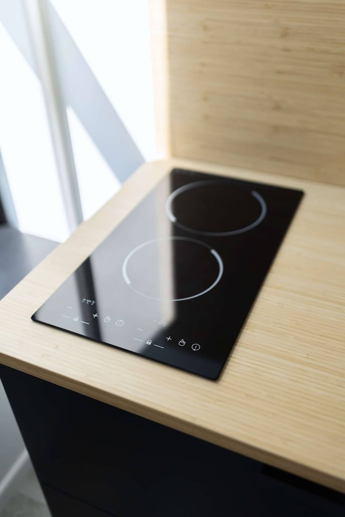 Una cocina de inducción negra sobre una encimera de madera.