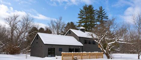 A large, single-story building with a sloped roof, surrounded by snow-covered ground and trees.