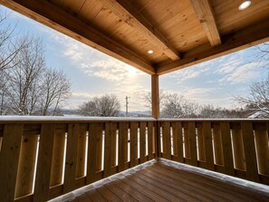 Un ponte di legno con ringhiera, cielo sereno e alberi spogli sullo sfondo.