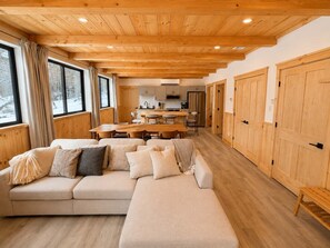 A modern interior with a wooden ceiling, a large sofa, a dining area, and a kitchen. - Fox Perch | Nordic Design, Nature Escape in Stowe (Stowe)
