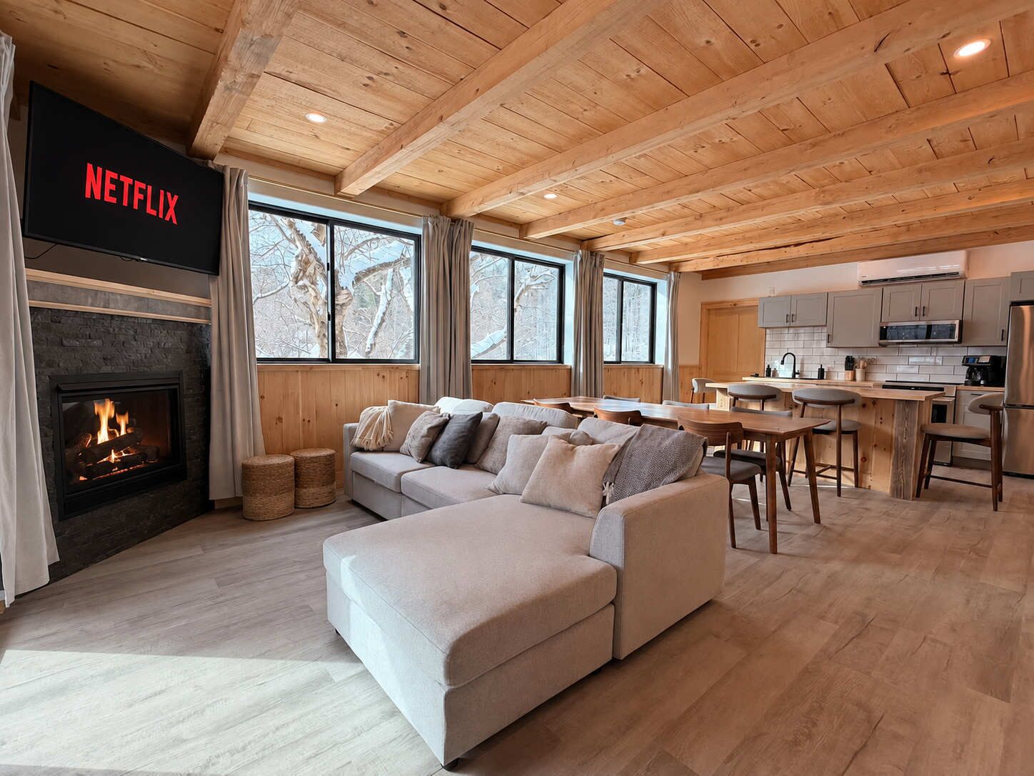 A modern living room with a fireplace, a sofa, a dining area, and a kitchen.