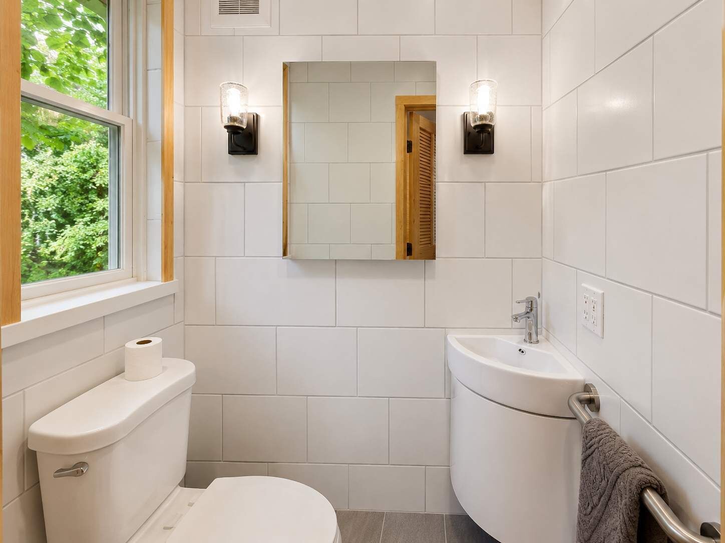 A modern bathroom with a toilet, sink, and mirror.