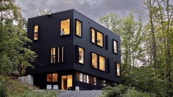 A modern black building with multiple windows, surrounded by trees.