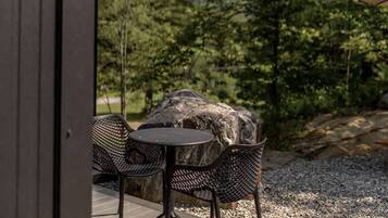 An outdoor seating area with a table and chairs, surrounded by a gravel path and a wooden deck.