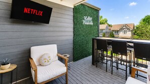 A covered outdoor area with a Netflix sign, a wall with 'Hello Nashville' text, and outdoor furniture. - Music-Themed Nashville Home | 4BR, 4 Baths & Bunk (Nashville)