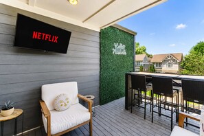 A covered outdoor area with a Netflix sign, a wall with 'Hello Nashville' text, and outdoor furniture. - Music-Themed Nashville Home | 4BR, 4 Baths & Bunk (Nashville)