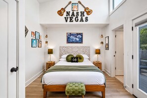 A bedroom with a bed, bedside tables, a green ottoman, a wall with guitars and the text 'NASH VEGAS', and a framed picture above the bed. - Music-Themed Nashville Home | 4BR, 4 Baths & Bunk (Nashville)